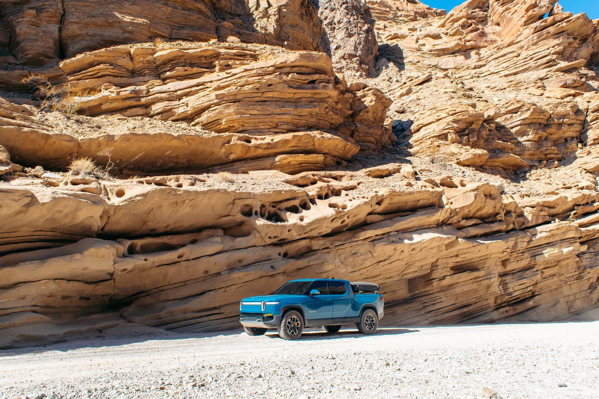 Rivian dwarfed by ancient sandstone layers. Nature wins.
